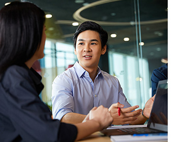 Photo of a customer sitting at a table with a Red Hat partner, the clients hands rest upward as the partners hands rest on her open laptop.